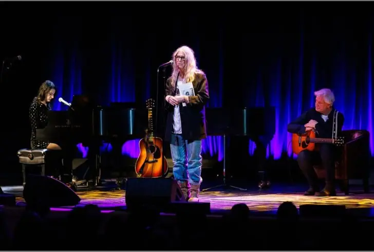 Patti Smith on stage with "Bread of Angels" memoir cover